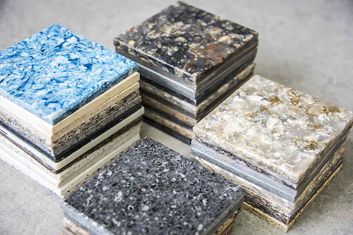 a colection of mutiple samples of types of quartz. The image shows stacks of small squares of quartz stone each with a different color/design. they are stacked on top of each other with 4 stacks of different height. 