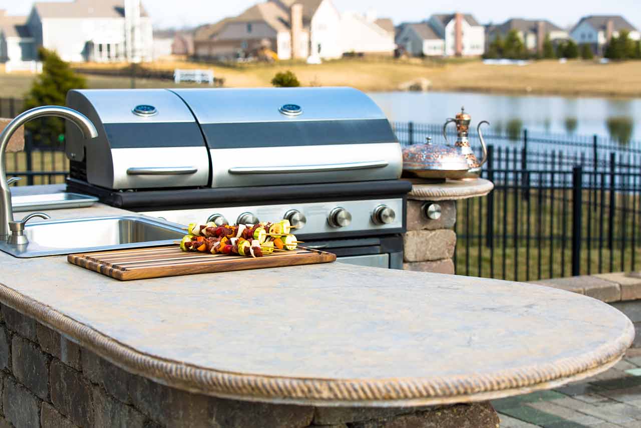 Image of an outdoor kitchen with a grill, sink, and granite countertops.